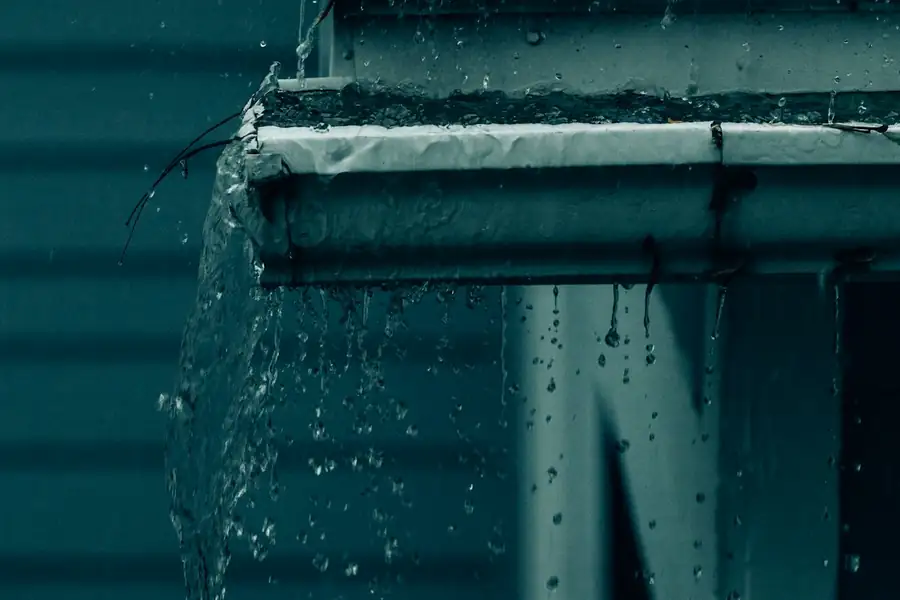 Water pouring from a downspout down the side of a house